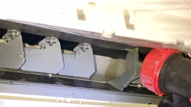 塗装道具でエアコン洗浄液を水で洗い流しています・藤原ペイント